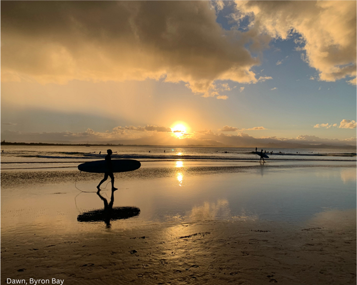 Surfer walking along Clarks Beach at dawn, Byron Bay